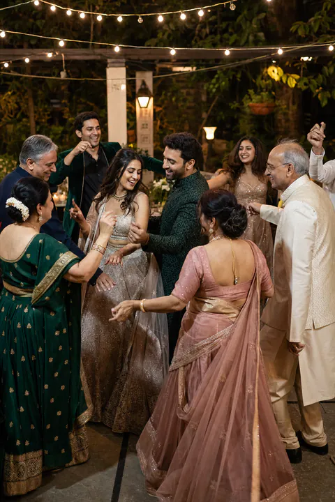 An Indian newly married couple dancing with parents and friends at an intimate garden reception