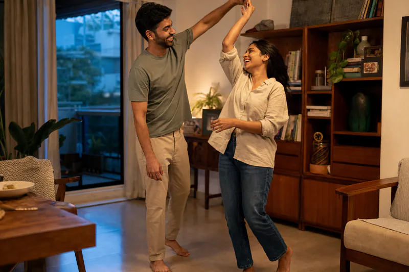 A young Indian couple dancing together in their sunlit home